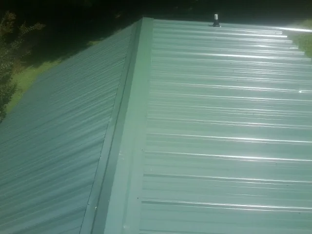 New green metal panels meeting at the ridge of a roof — Flat Roof Repair work by our crew in Cashion