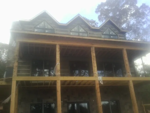 Dormers and porch framing on a large log home under construction — Roof Coating work by our crew in Cashion