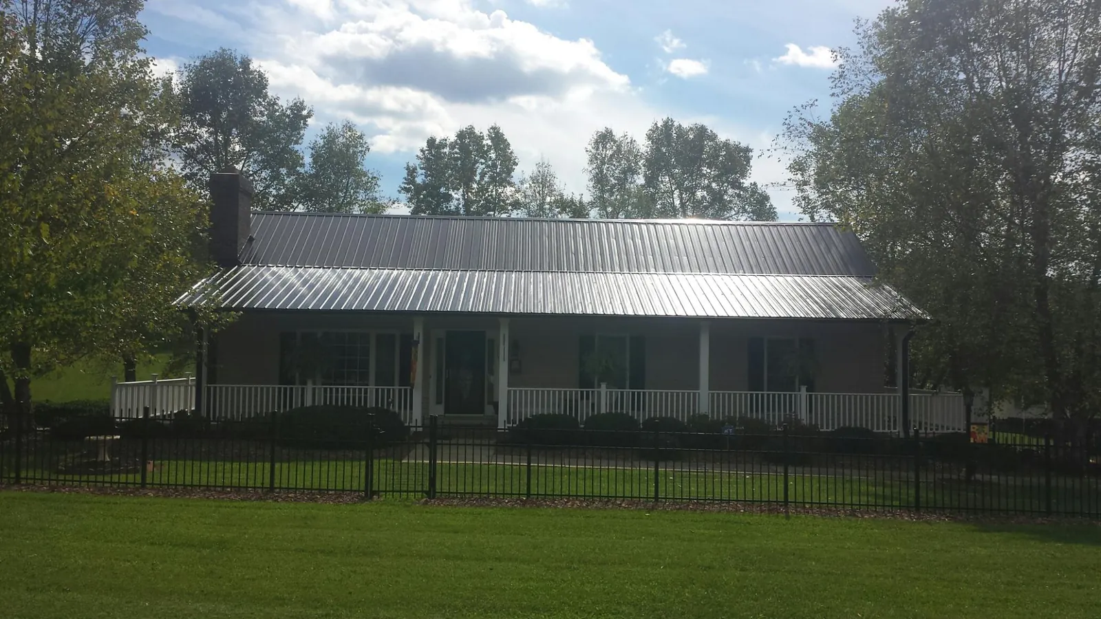 Gray metal roof on a brick ranch with a full width front porch — Gutter Guard Installation work by our crew in Cashion