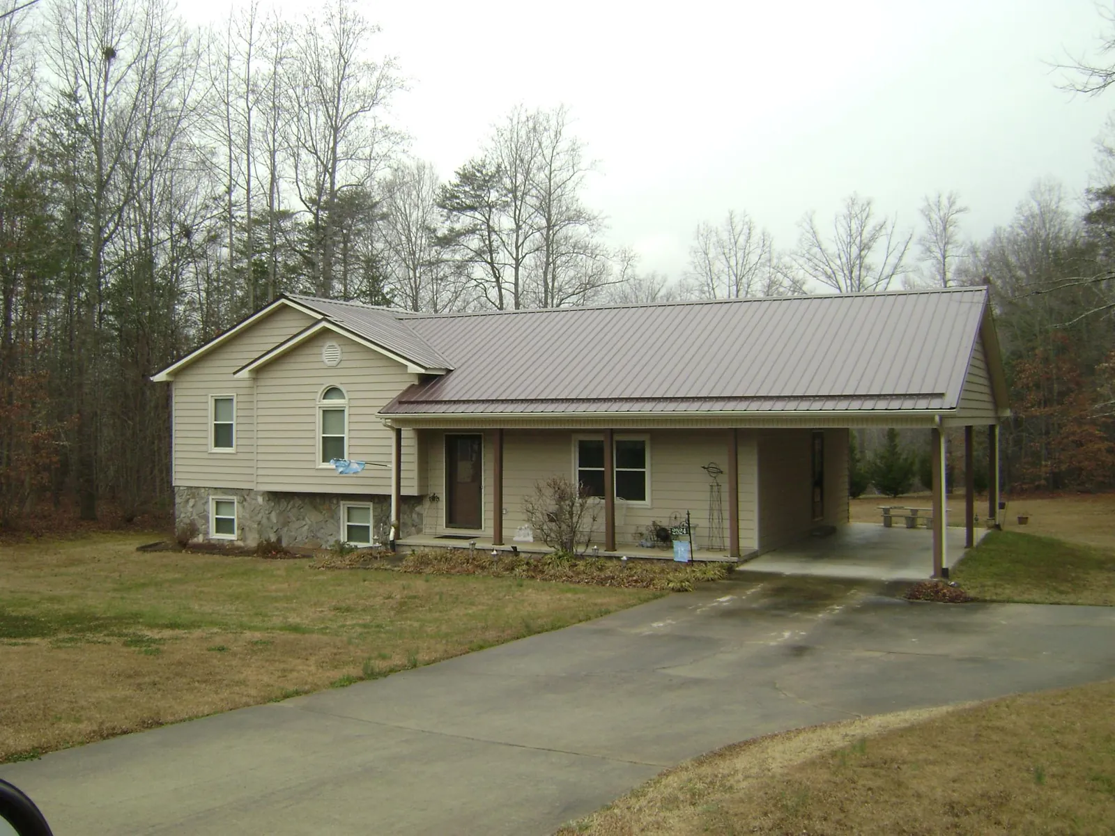 Brown metal roof on a tan split level home with an attached carport in Cashion