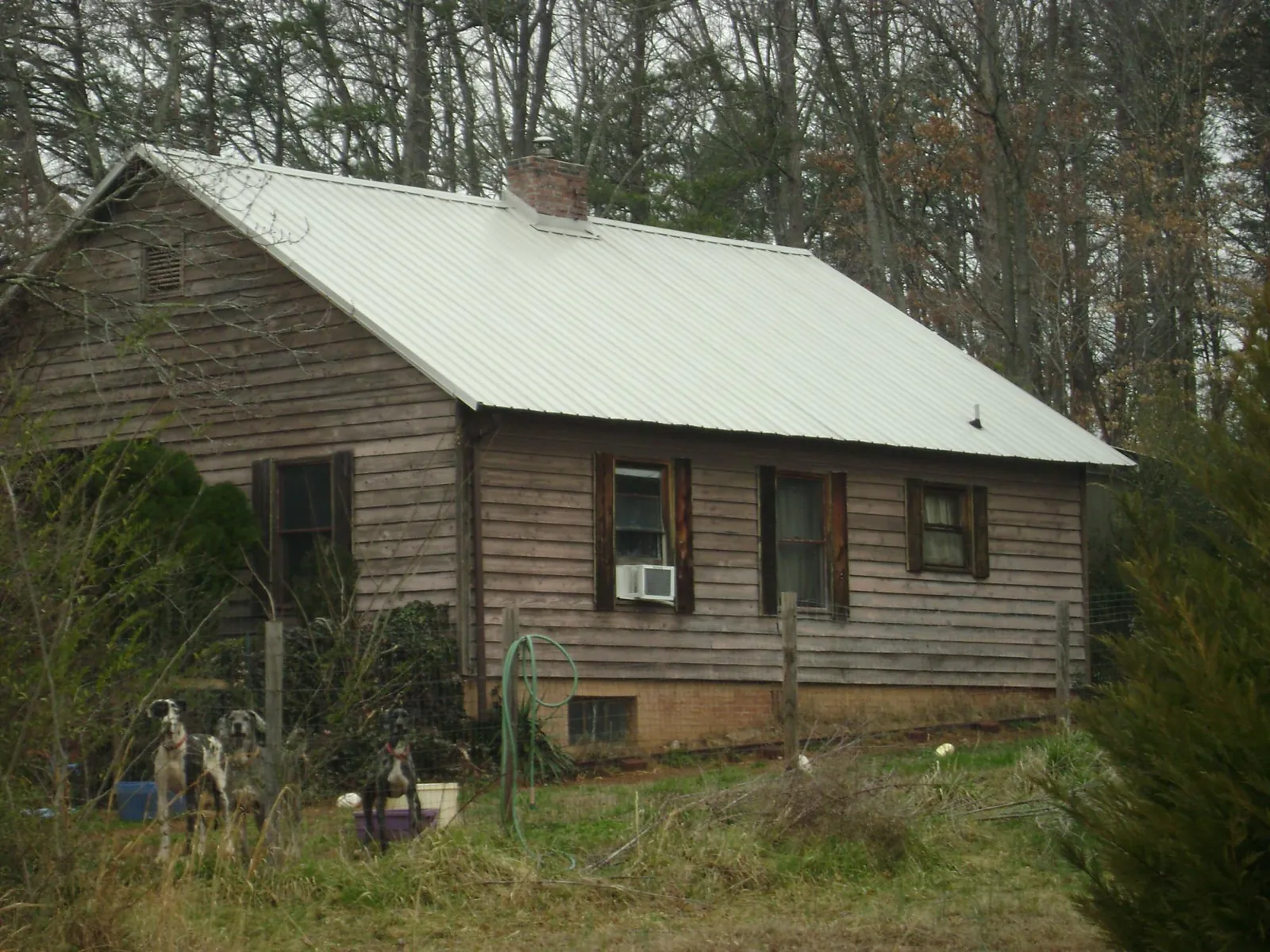 White metal roof on an old wood sided farmhouse, from a Metal Roof Installation job in Cashion