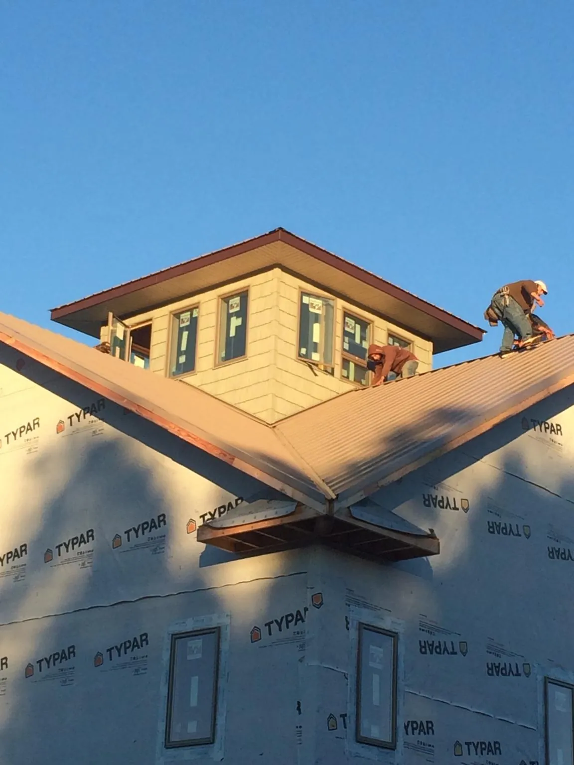 Roofers working around a rooftop cupola on a new metal roof at sunset — Roof Waterproofing in Cashion by Roofing Brothers